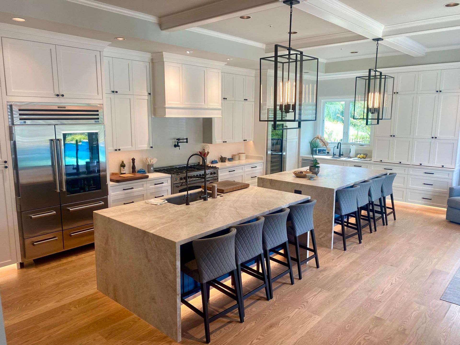 A large kitchen with white cabinets , stainless steel appliances , and a large island.