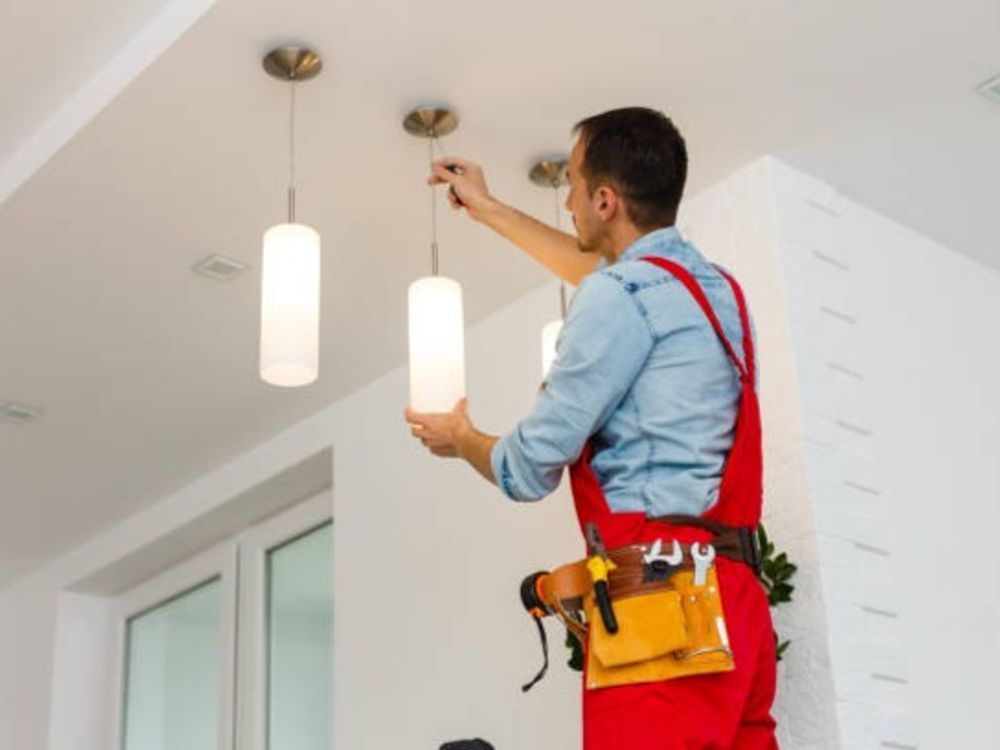 A man is installing a light fixture on the ceiling.