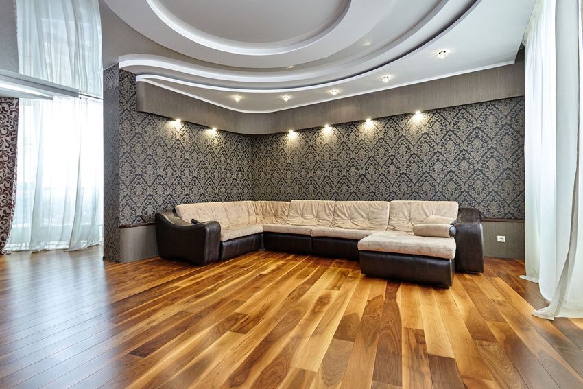 A living room with a large sectional couch and hardwood floors.