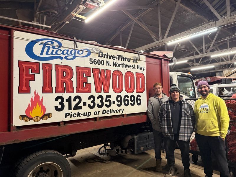Three men stand beside a Chicago Firewood truck with its phone number displayed.