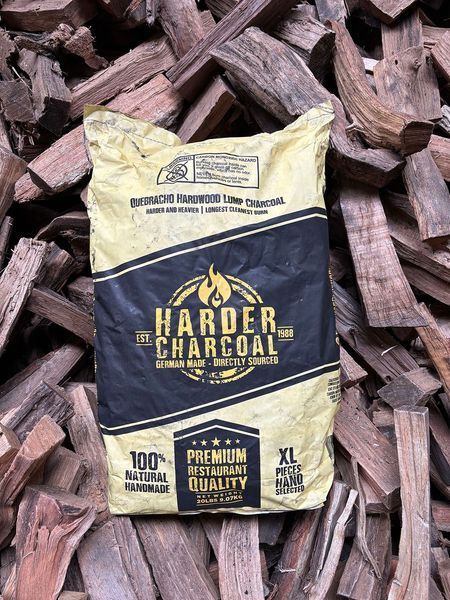 Bag of Harder Charcoal on a pile of wood. Yellow, black, and white packaging.