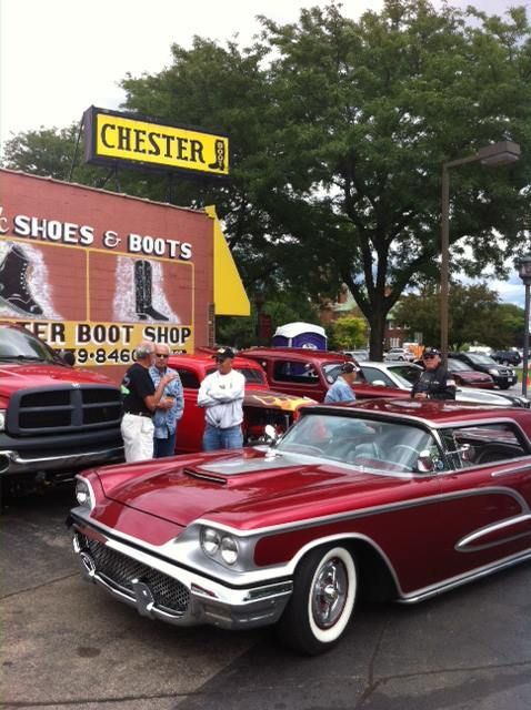 A red car is parked in front of a chester shoes and boots store