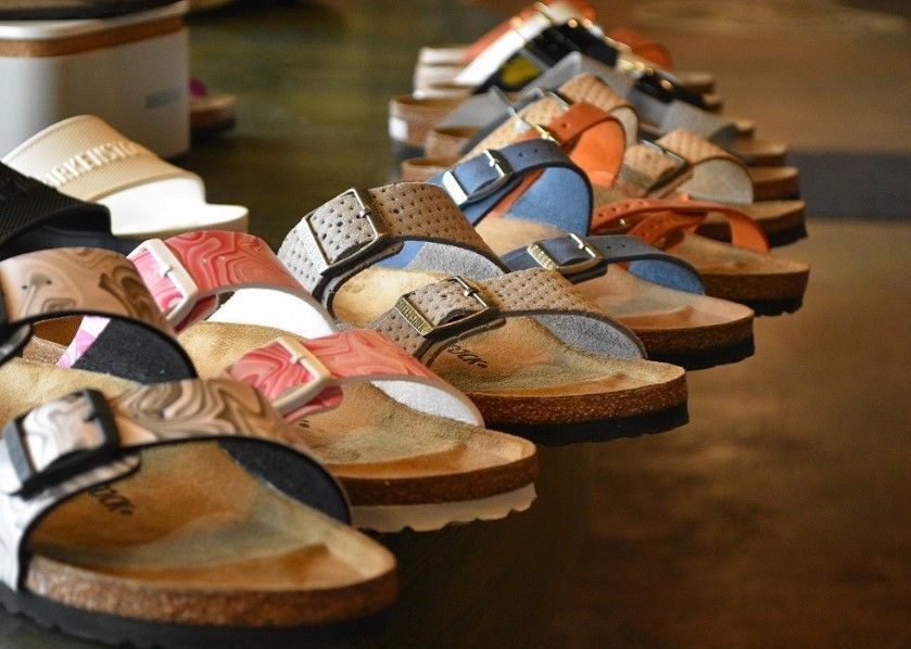 A row of sandals are lined up on a table.