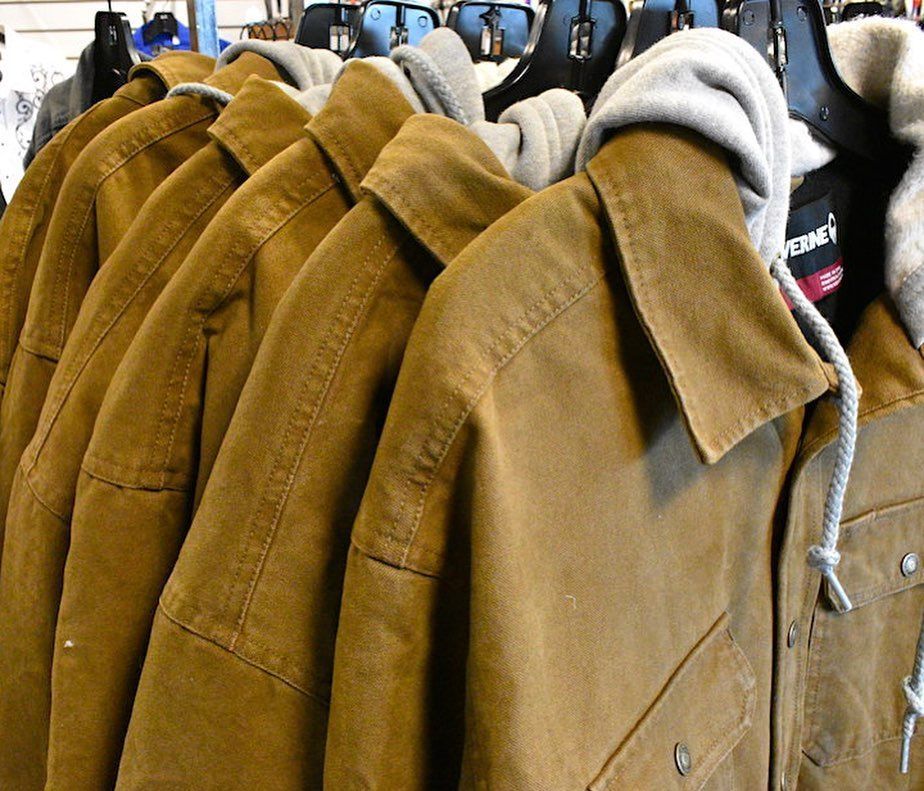 A row of brown jackets are hanging on a rack