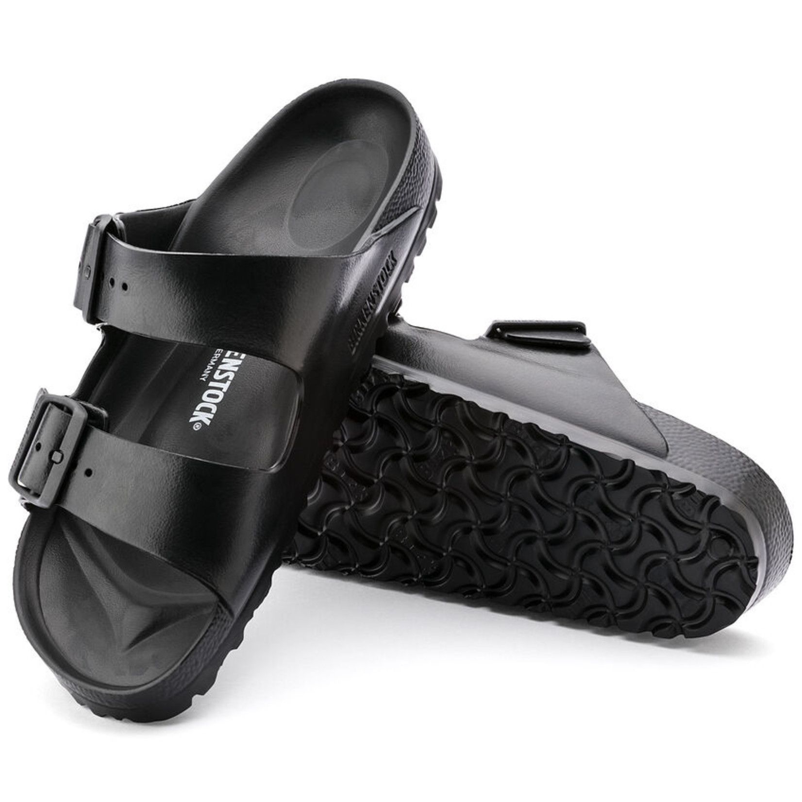 A pair of black birkenstock sandals are stacked on top of each other on a white background.