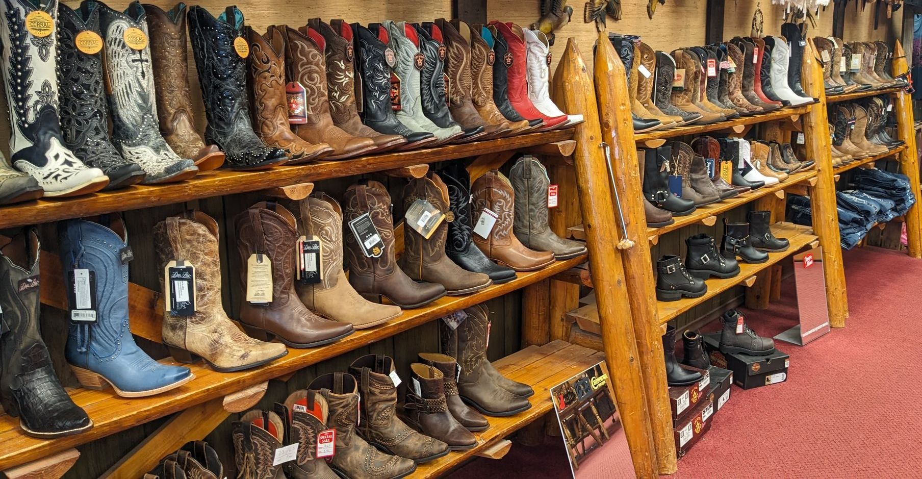 A row of cowboy boots are lined up on shelves in a store.