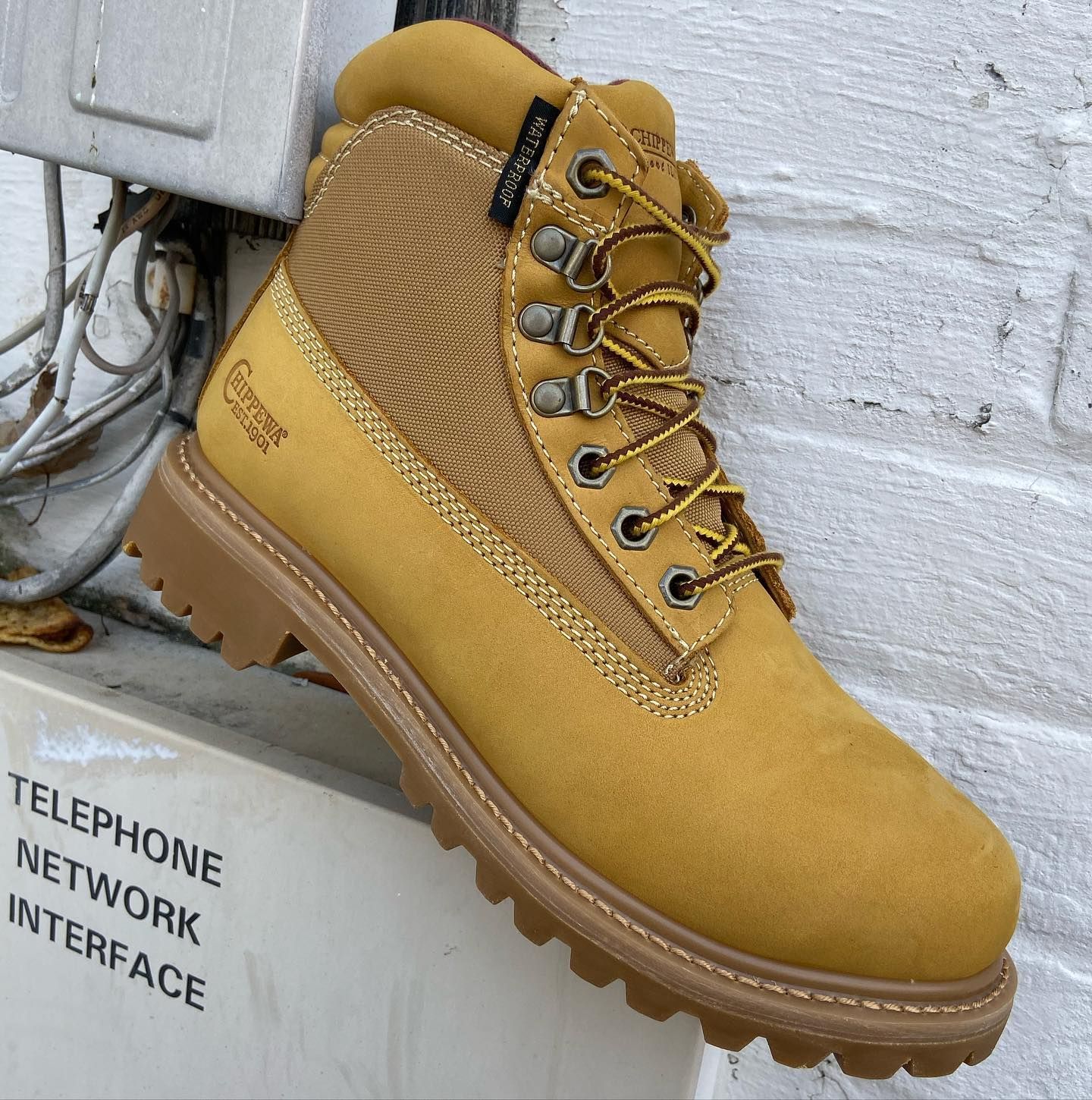 A pair of yellow boots is sitting next to a sign that says telephone network interface