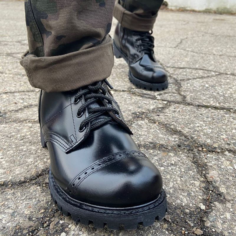 A person wearing a pair of black combat boots