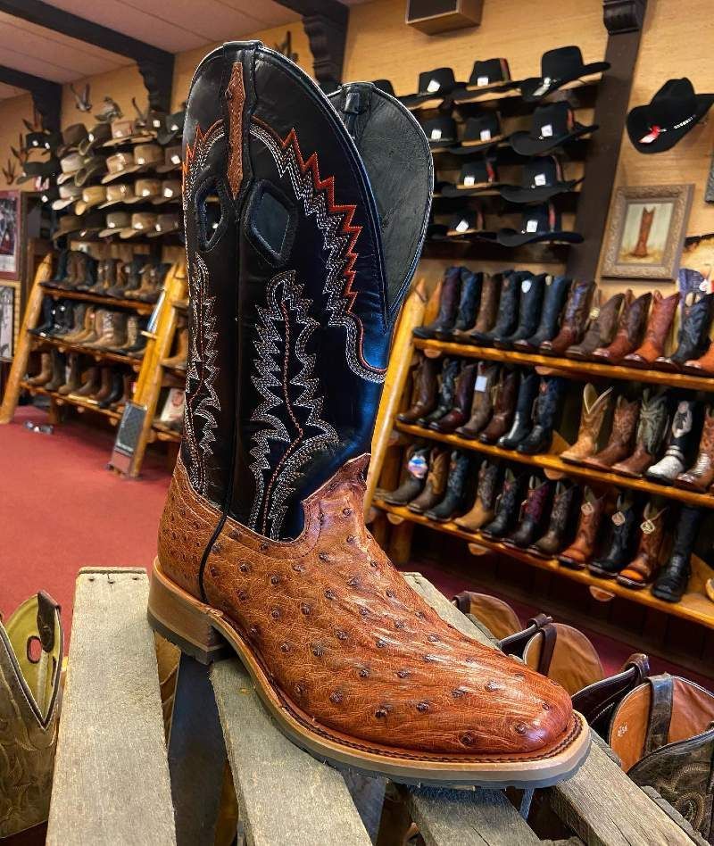 A pair of cowboy boots are sitting on a wooden shelf in a store.