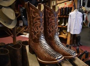 A pair of cowboy boots are sitting on top of a wooden table in a store.
