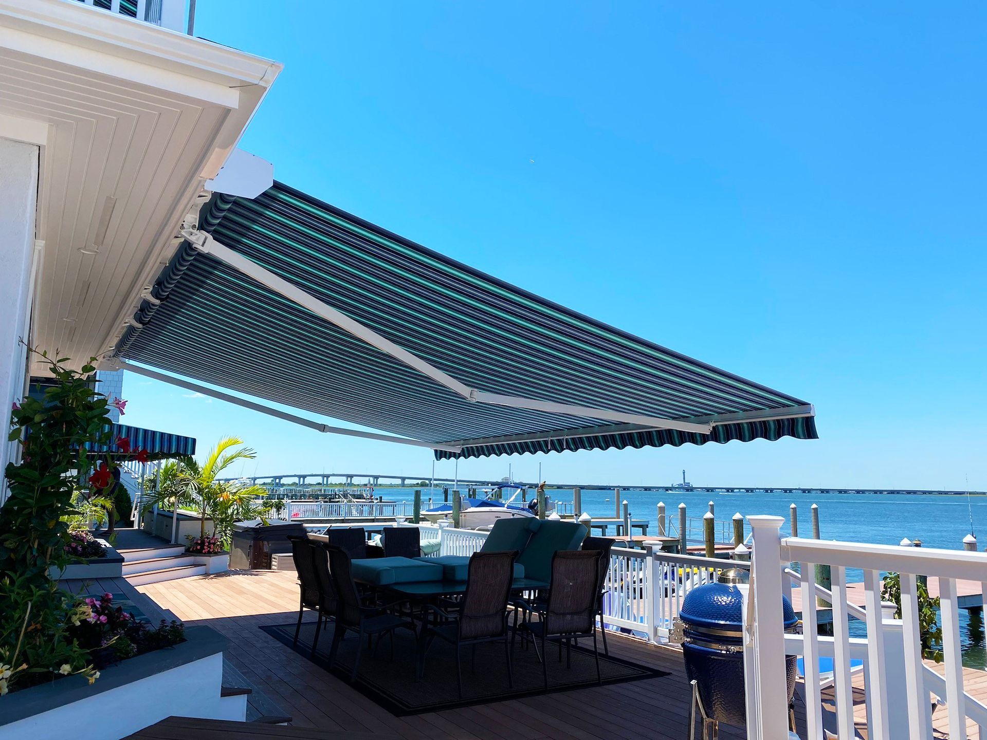 A patio with a table and chairs under an awning overlooking the ocean