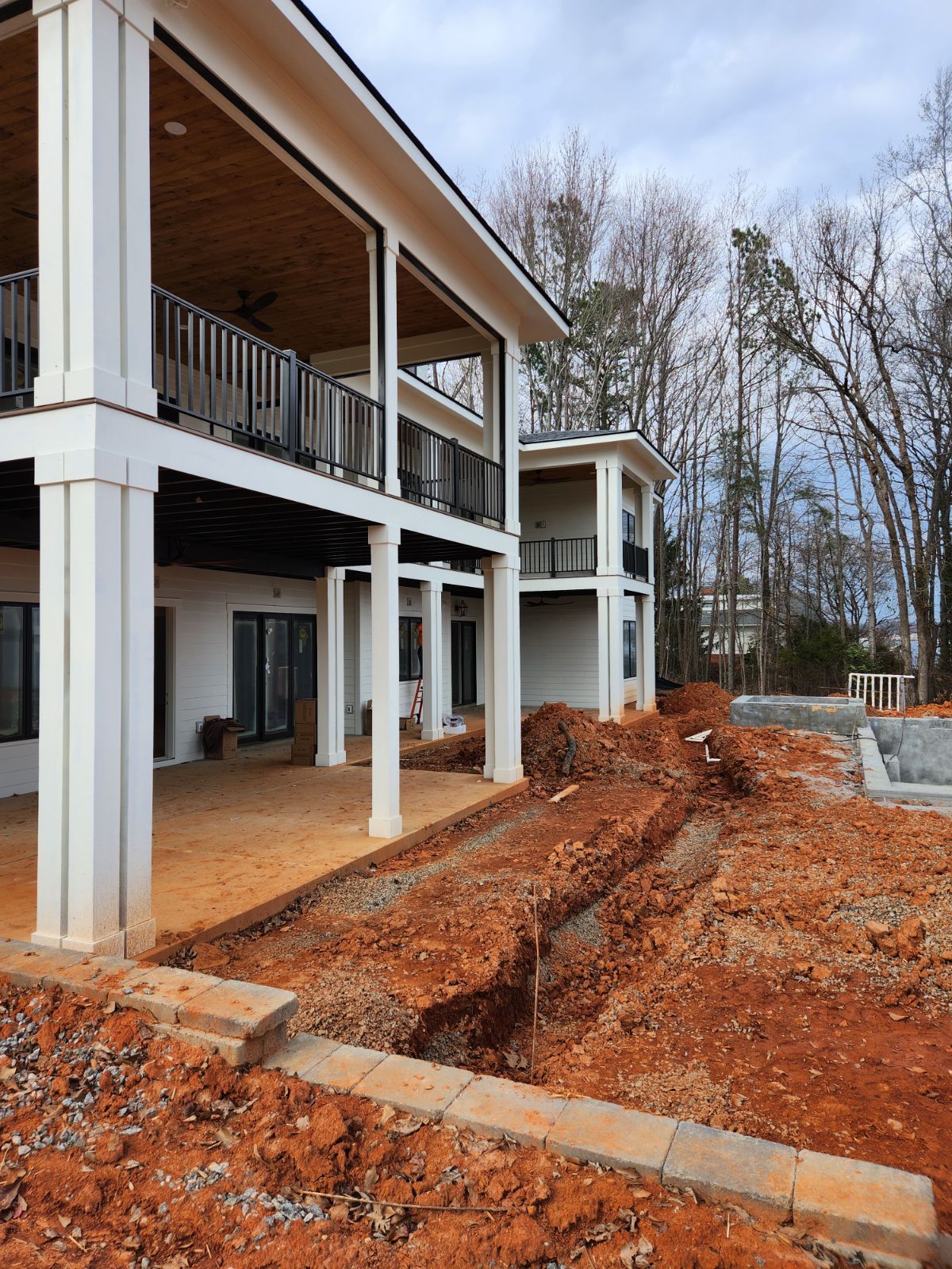 A large white house is being built in the middle of a dirt field