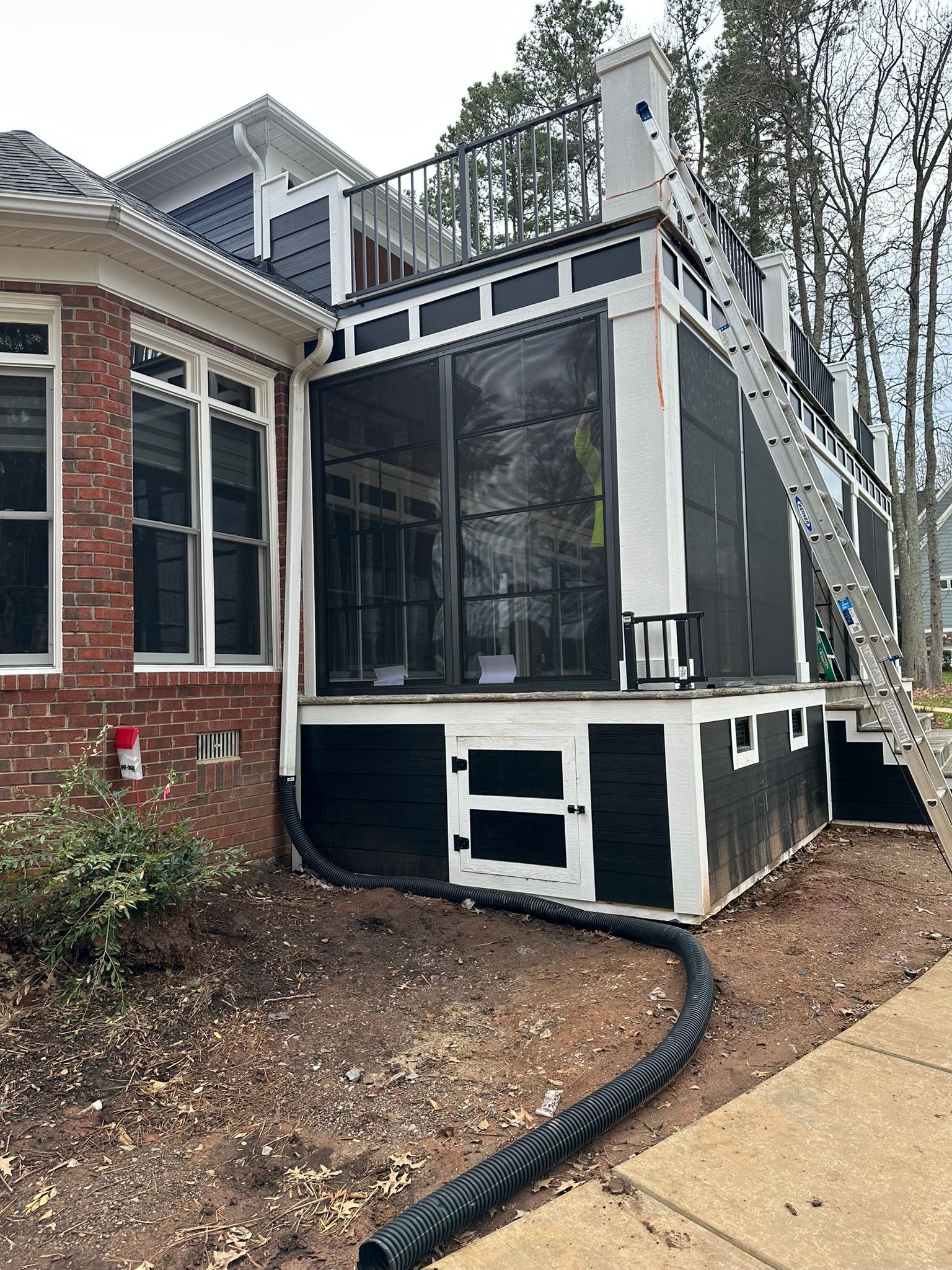 A black and white house with a screened in porch and stairs