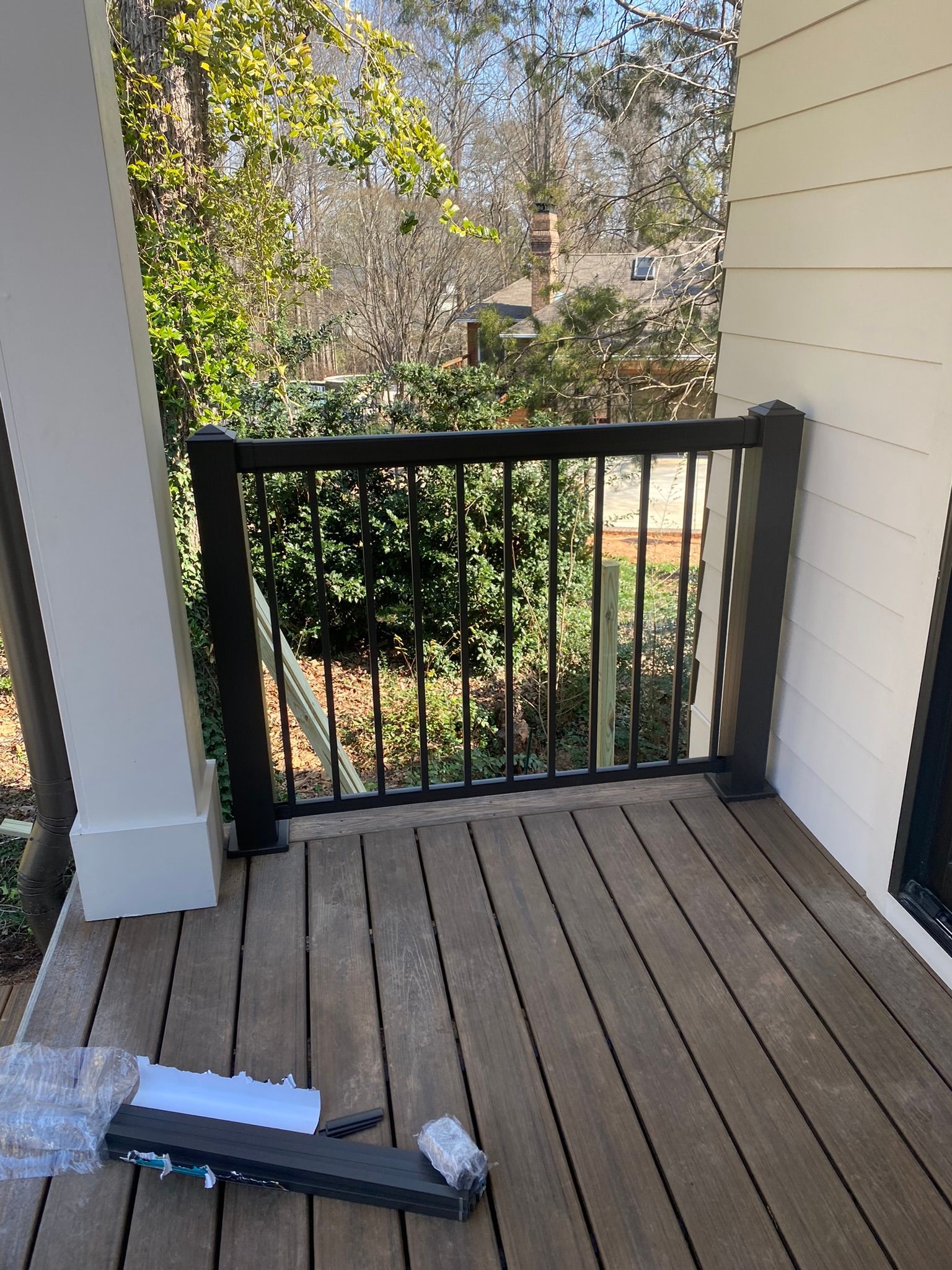 A wooden deck with a black railing and a window