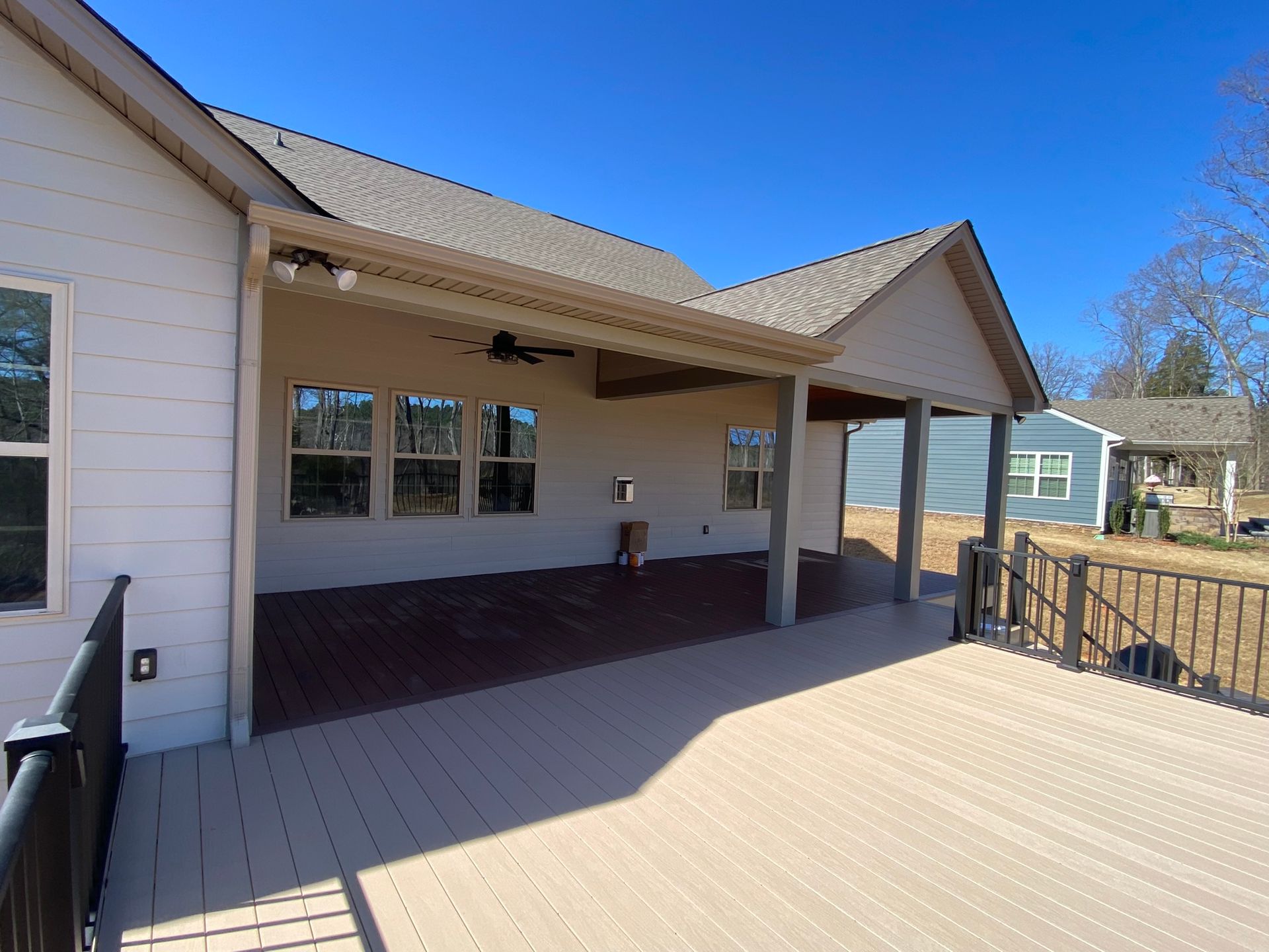 A large deck with a covered patio in front of a house