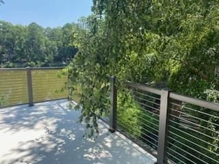 A balcony with a fence and trees in the background.