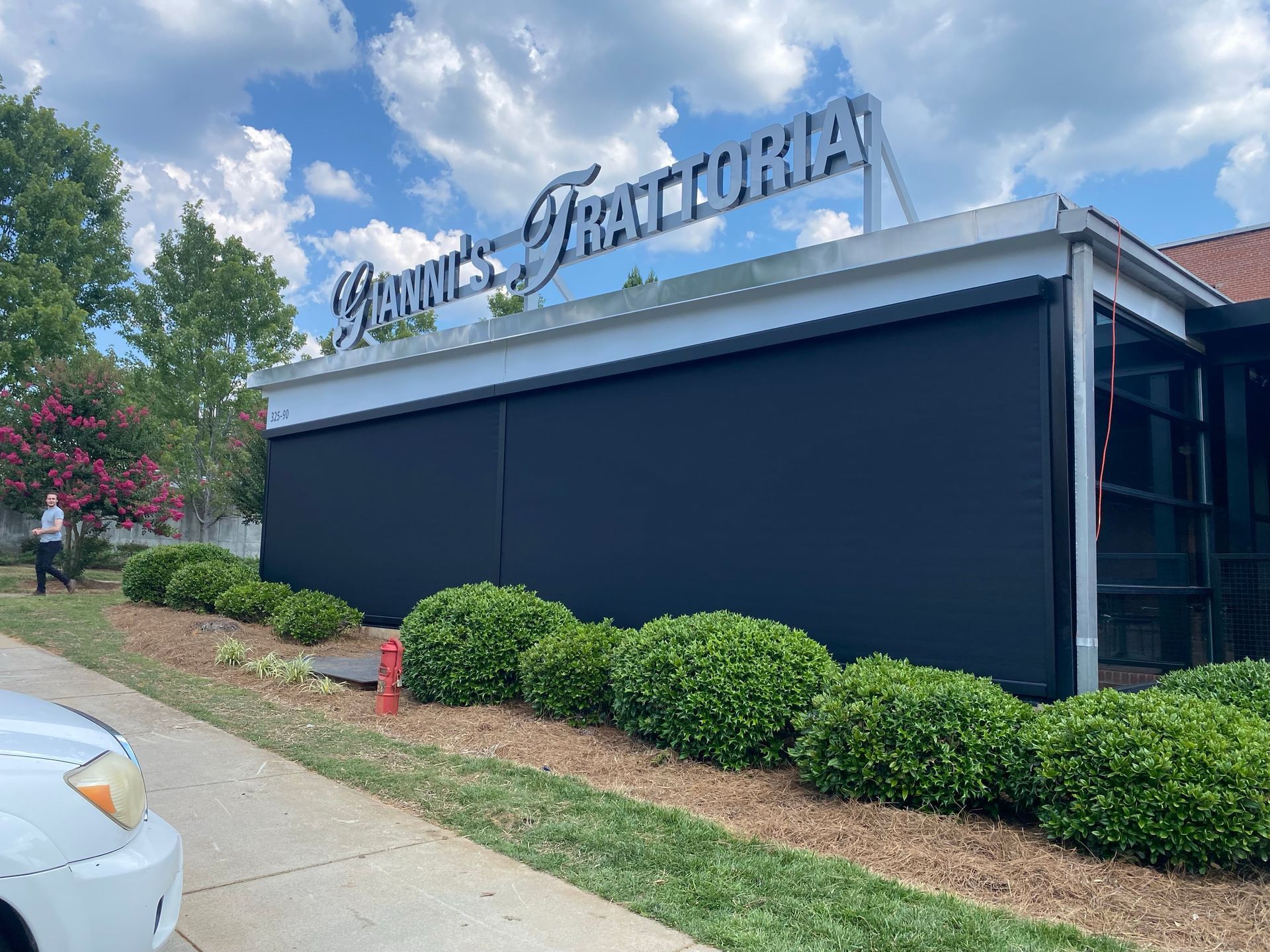 A white car is parked in front of a restaurant.