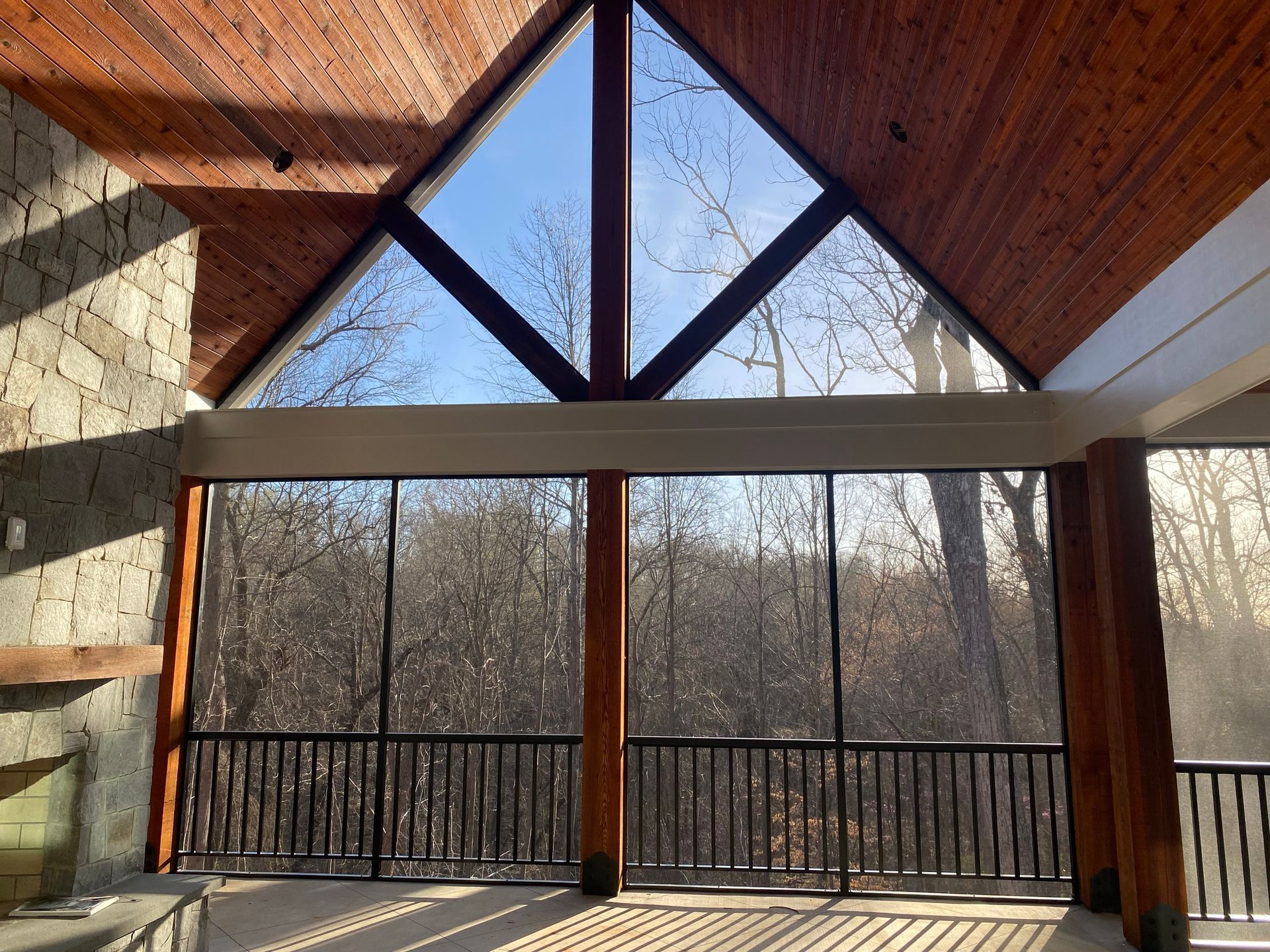 A screened in porch with a view of the woods