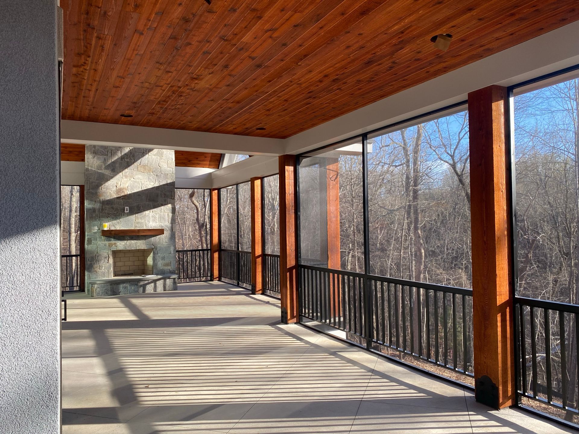 A screened in porch with a fireplace and trees in the background