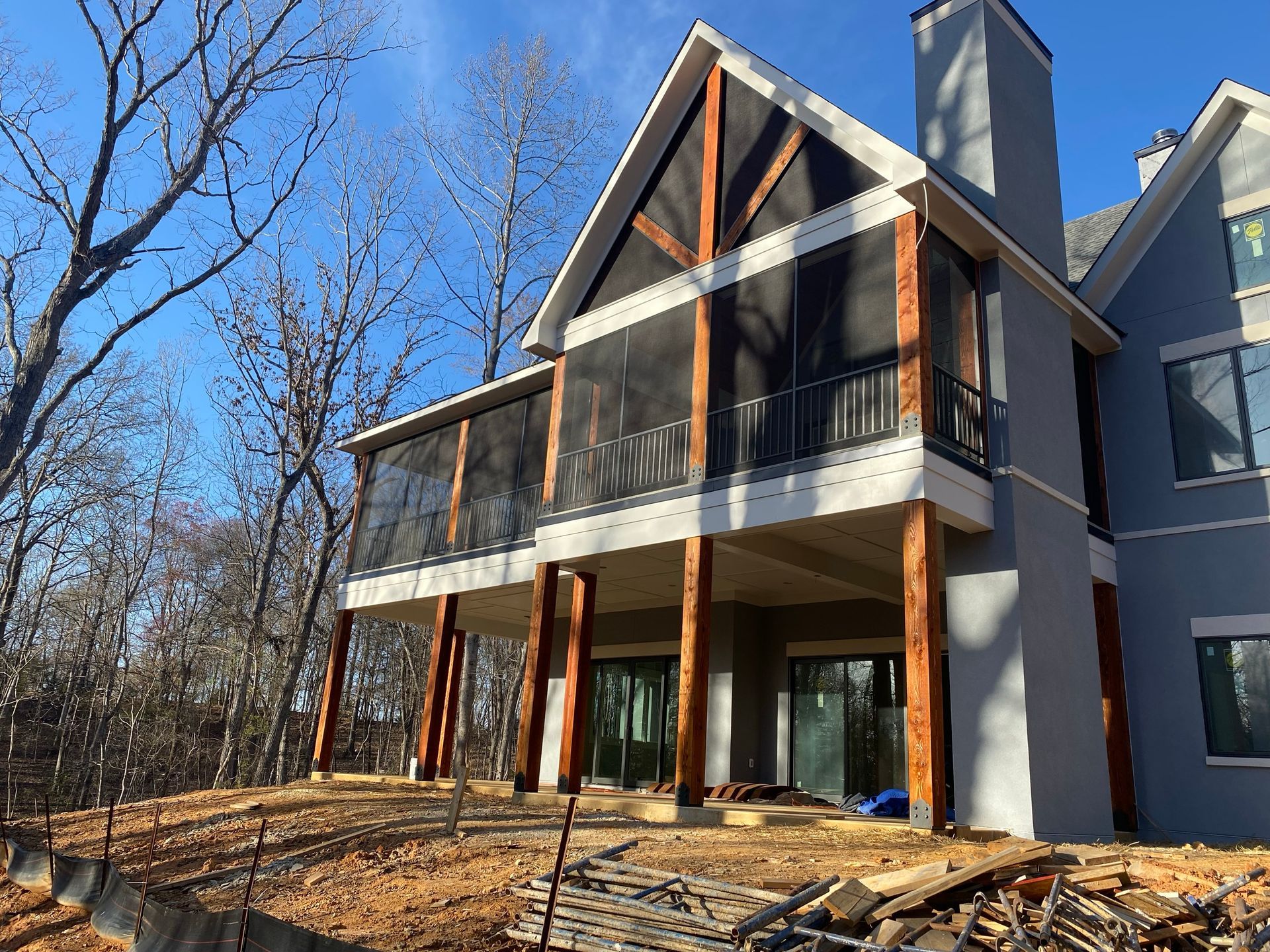 A large house with a screened in porch is surrounded by trees.
