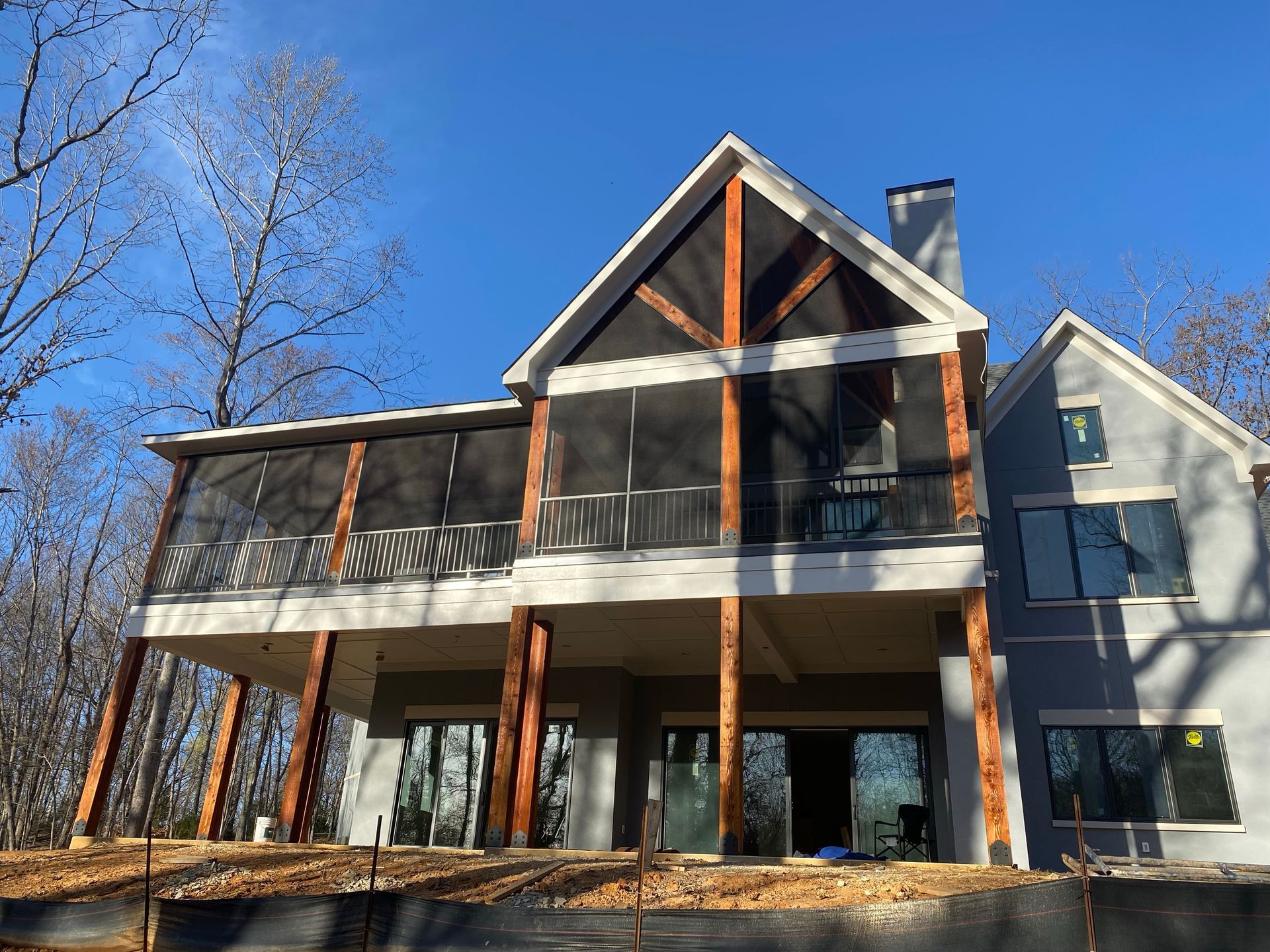 A large house with a screened in porch is sitting on top of a hill.