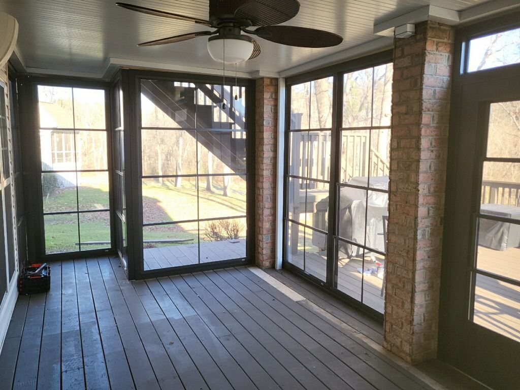 A screened in porch with a ceiling fan and lots of windows