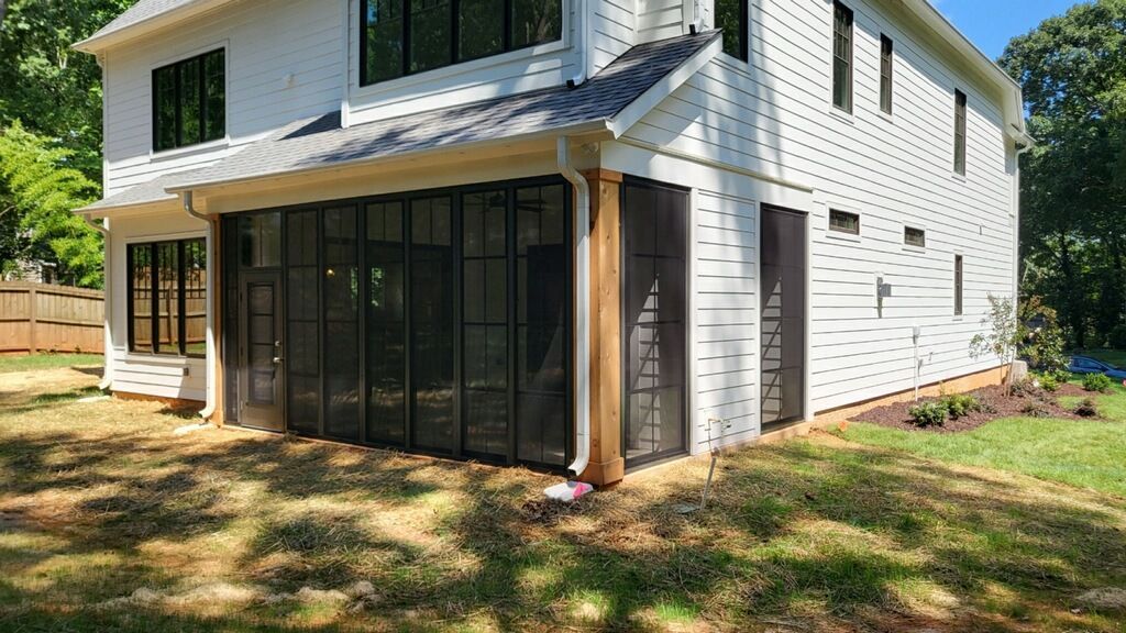 A white house with black windows and a screened in porch