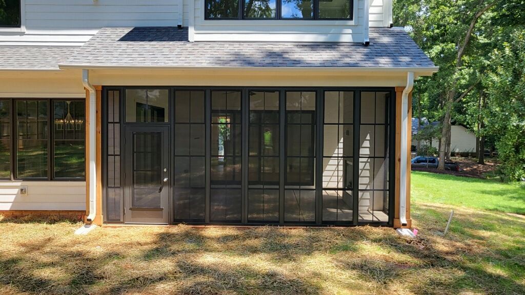 The back of a house with a screened in porch and a lot of windows