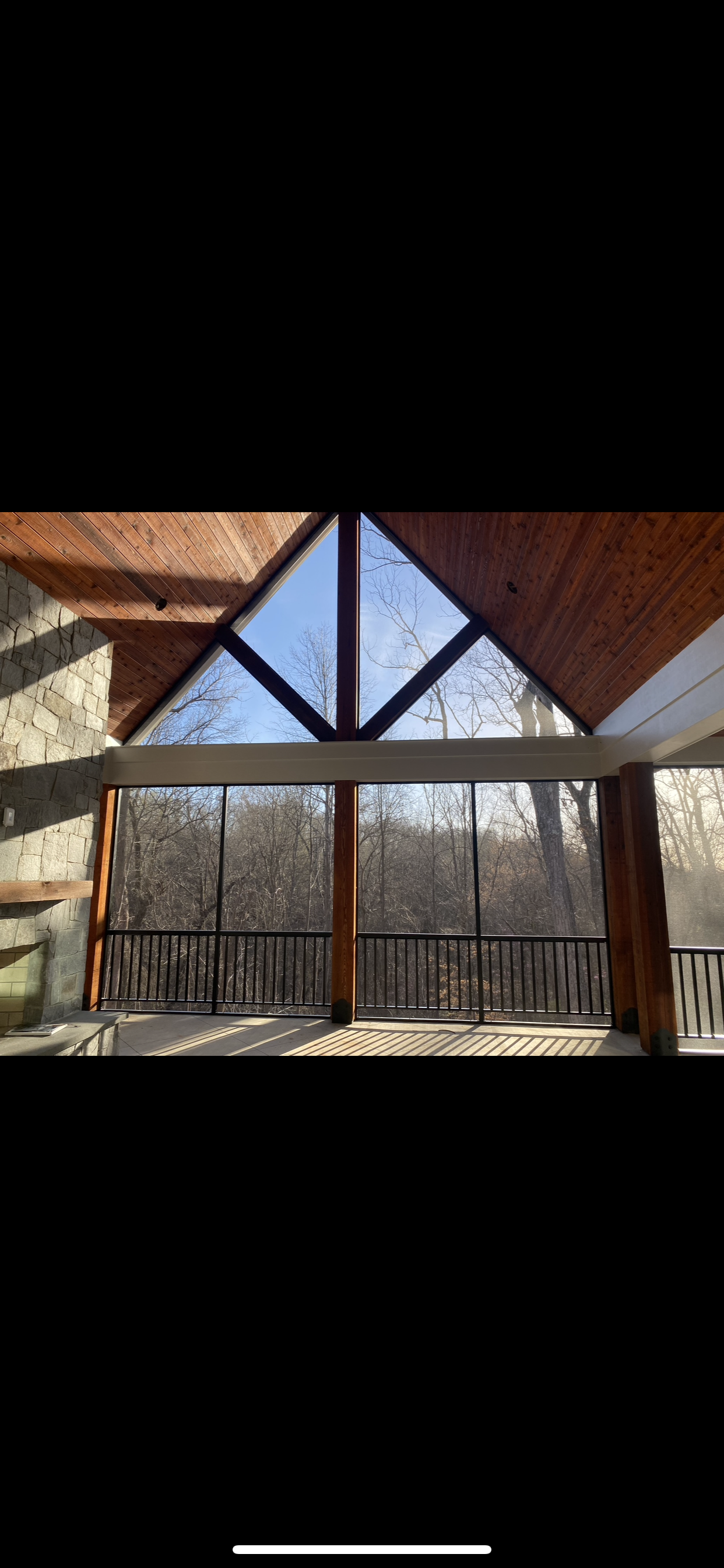 A screened-in porch with a vaulted ceiling and a view of the woods