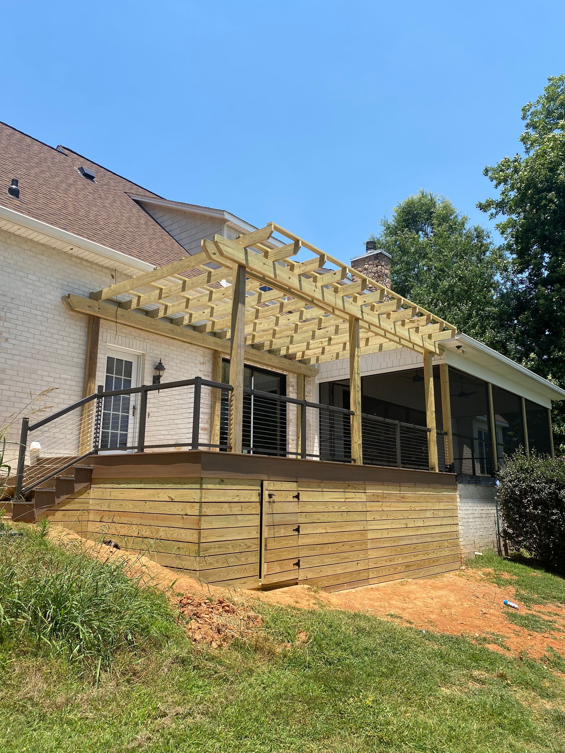 A wooden deck with cable railingson the back of a house.
