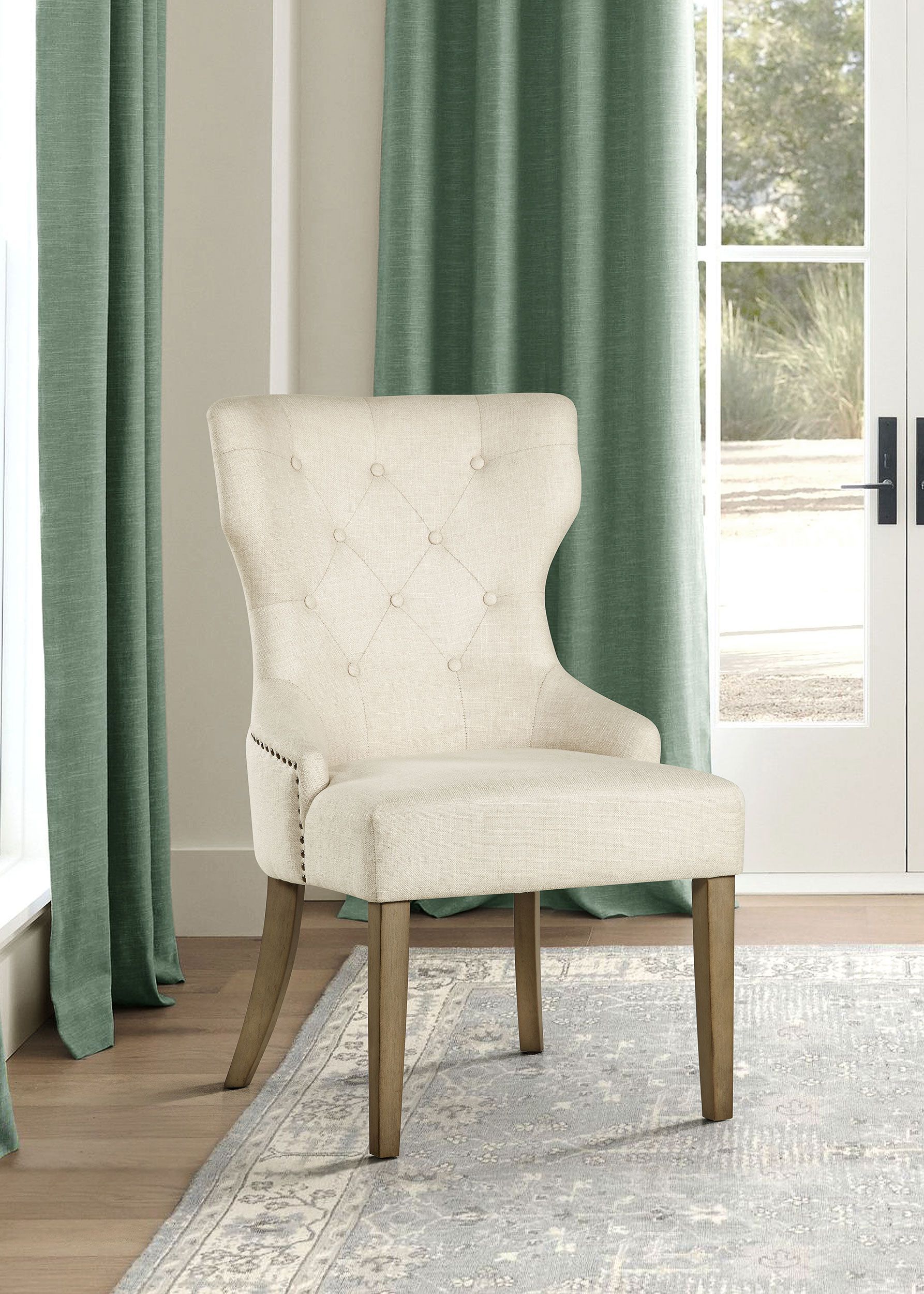 A white chair is sitting on a rug in a living room next to a window.