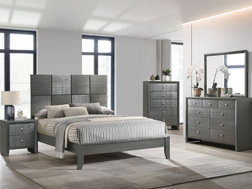 A bedroom with a bed , dresser , nightstand and mirror.