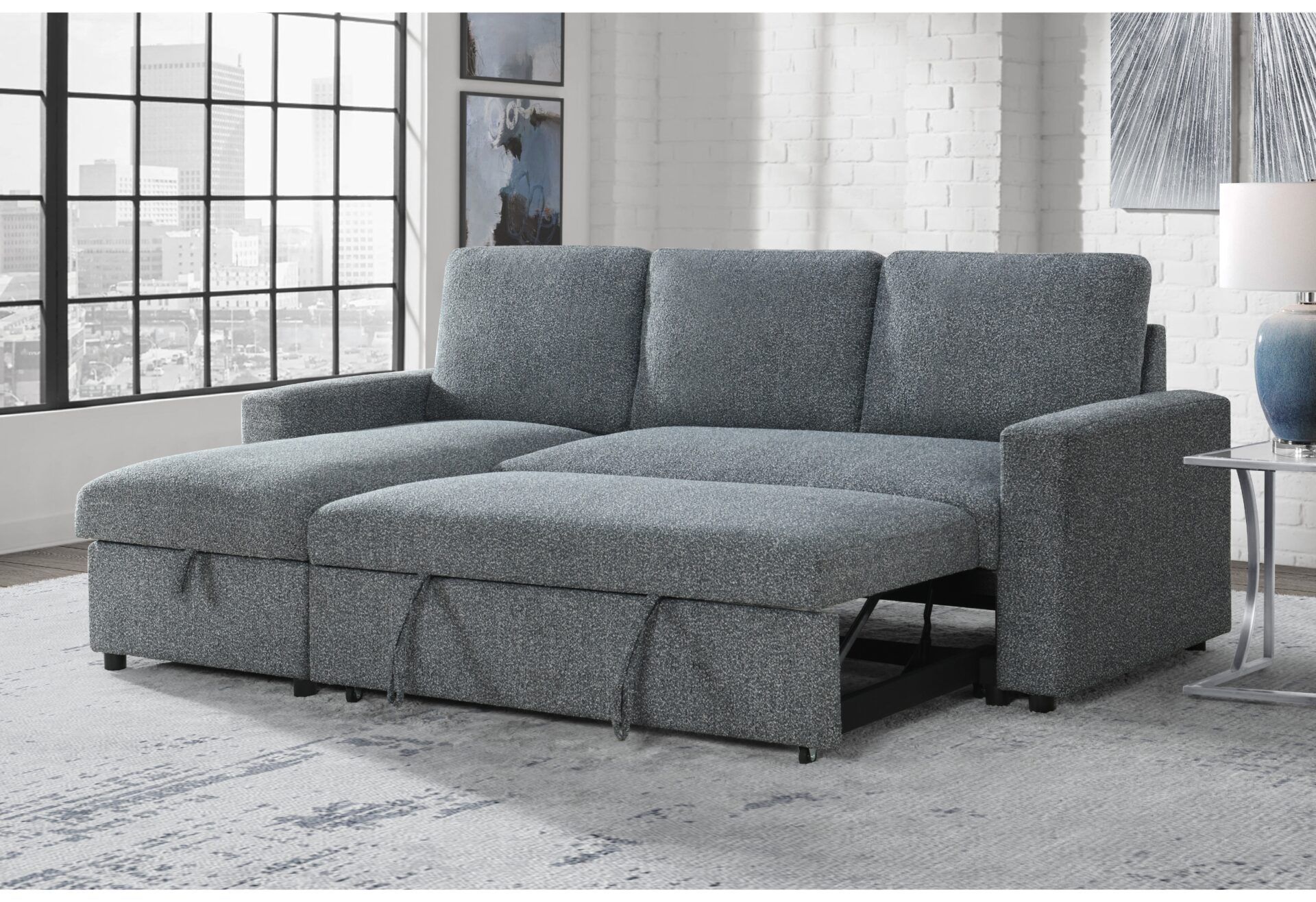 A gray sectional couch is pulled out to become a bed in a living room.