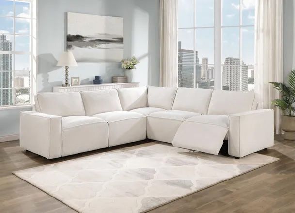 A living room with a white sectional couch and a rug.