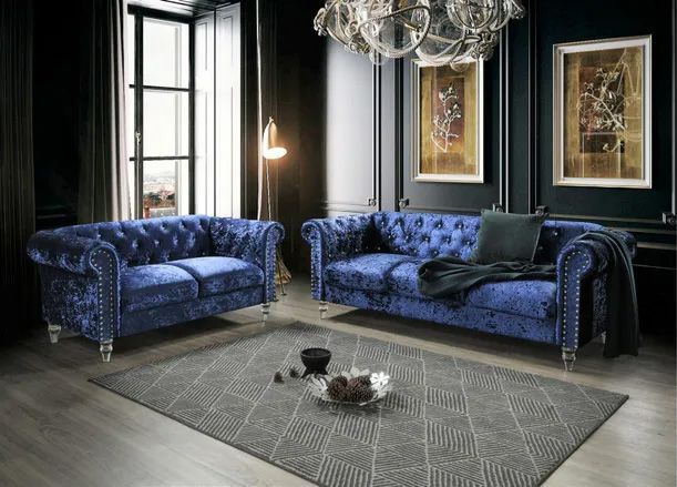 A living room with two blue couches and a rug.