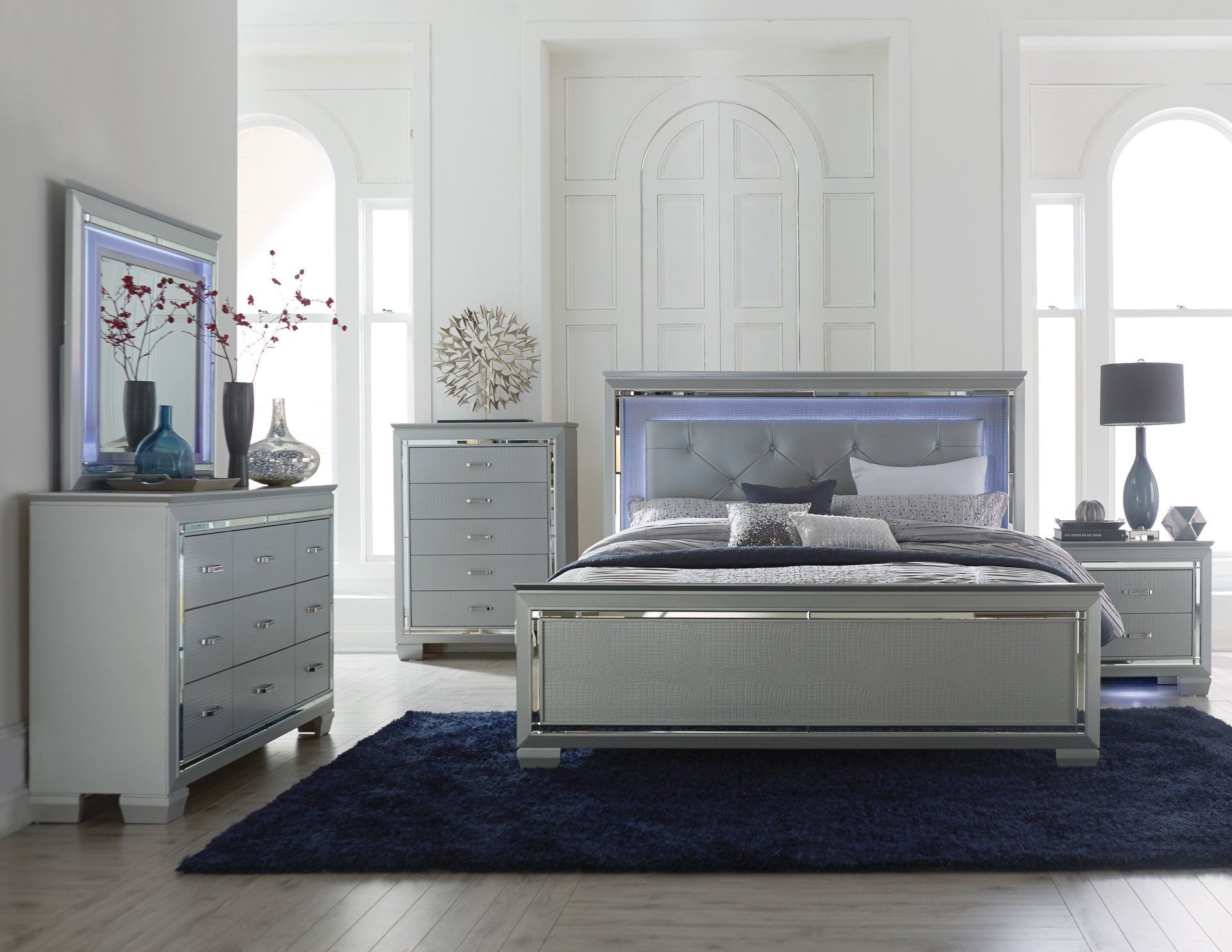 A bedroom with a bed , dresser , nightstand , mirror and rug.