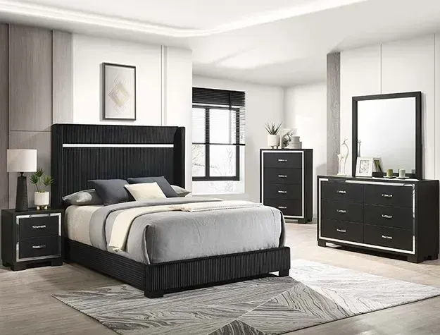 Black bedroom set with bed, dresser, chest, mirror, and nightstand in a bright room.