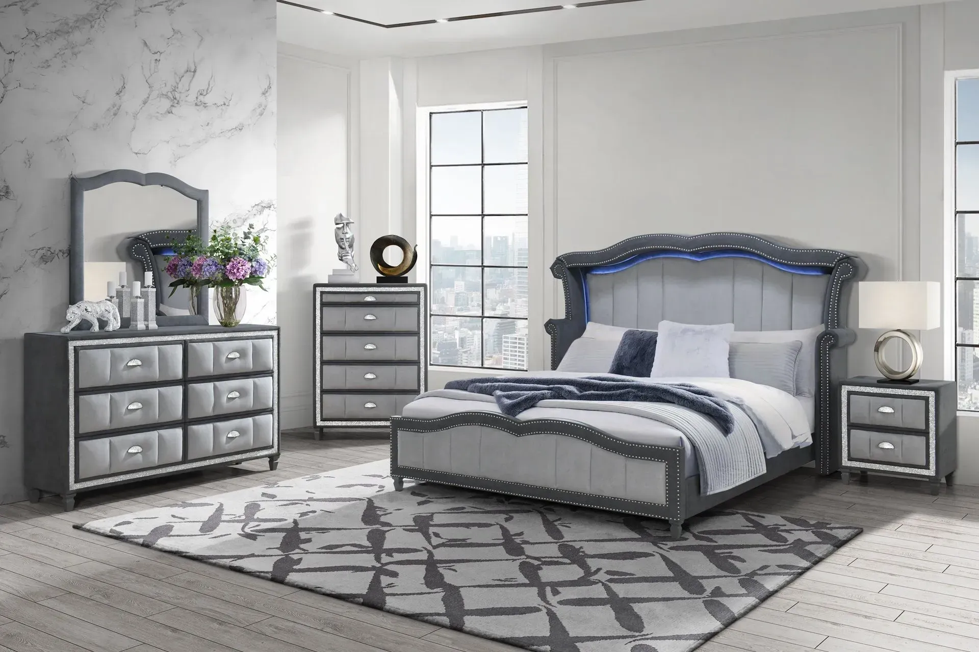Gray bedroom set with bed, dresser, chest, mirror, and nightstand on patterned rug.
