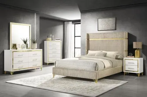 Bedroom furniture set: white and gold bed, dresser, chest, mirror, and nightstand in a gray room with rug.