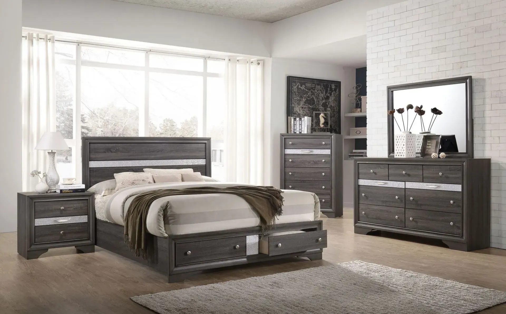 Bedroom furniture set: gray bed with storage, nightstand, dresser with mirror, and chest in a neutral room.