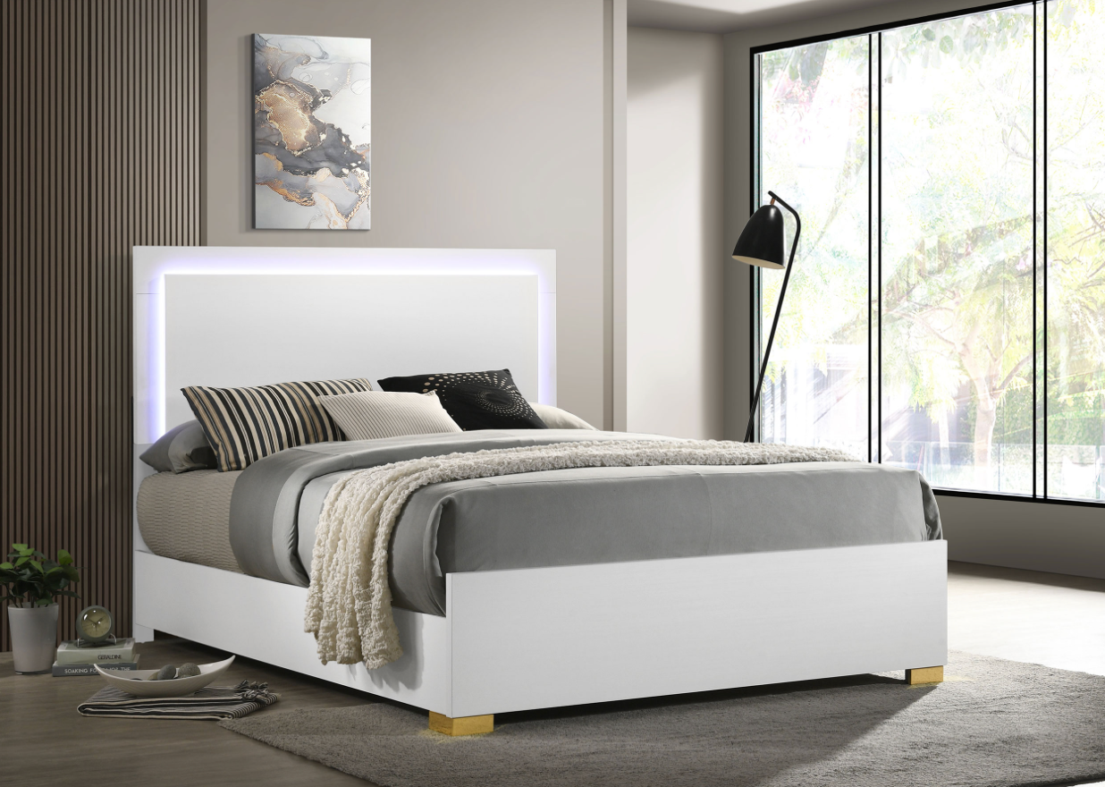 A white bed with a lighted headboard is in a bedroom next to a window.