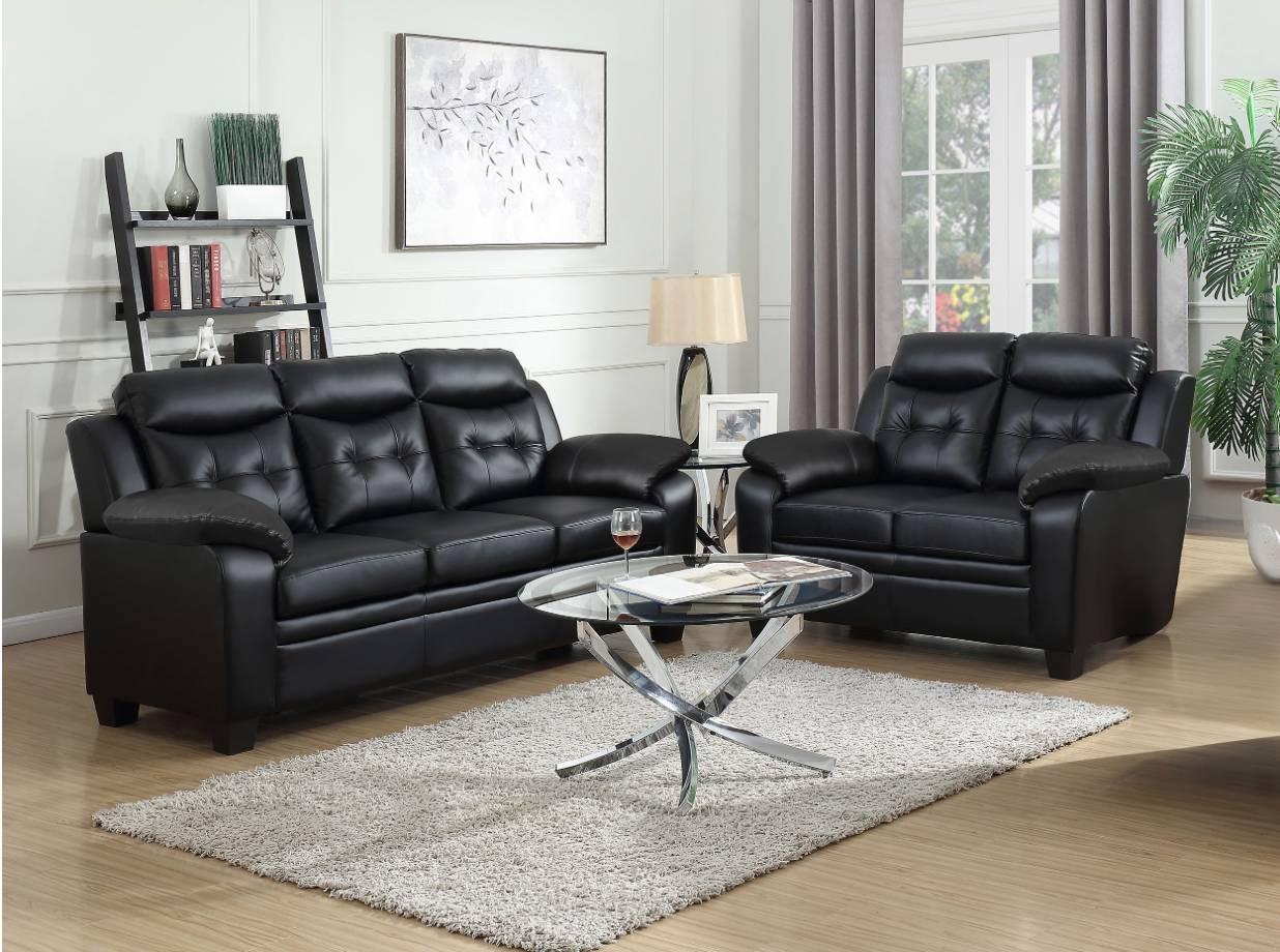A living room with two black leather couches and a coffee table