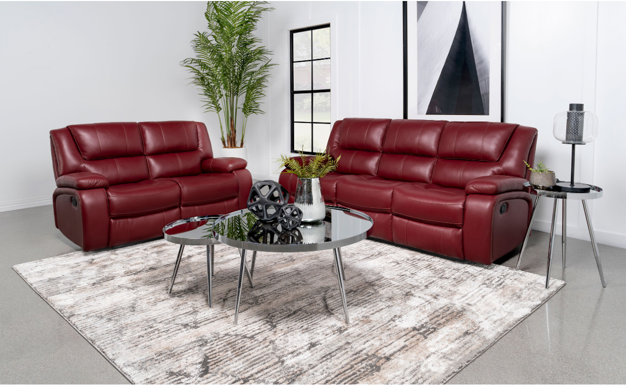 A living room with two red leather couches , a coffee table , and a rug.