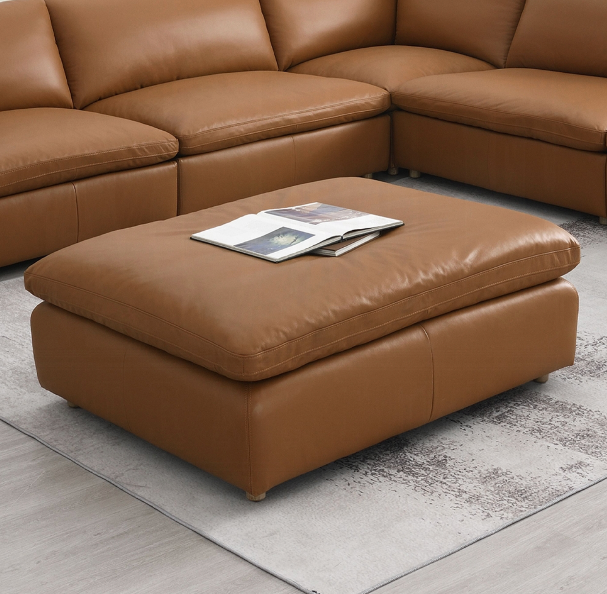 A brown leather ottoman is sitting in front of a brown sectional couch.