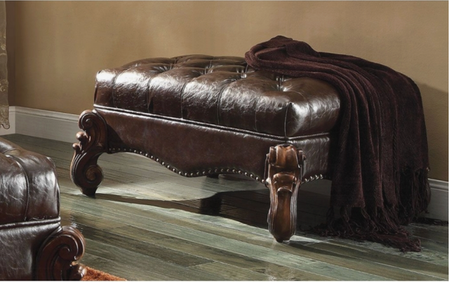 A brown leather ottoman with a blanket on it