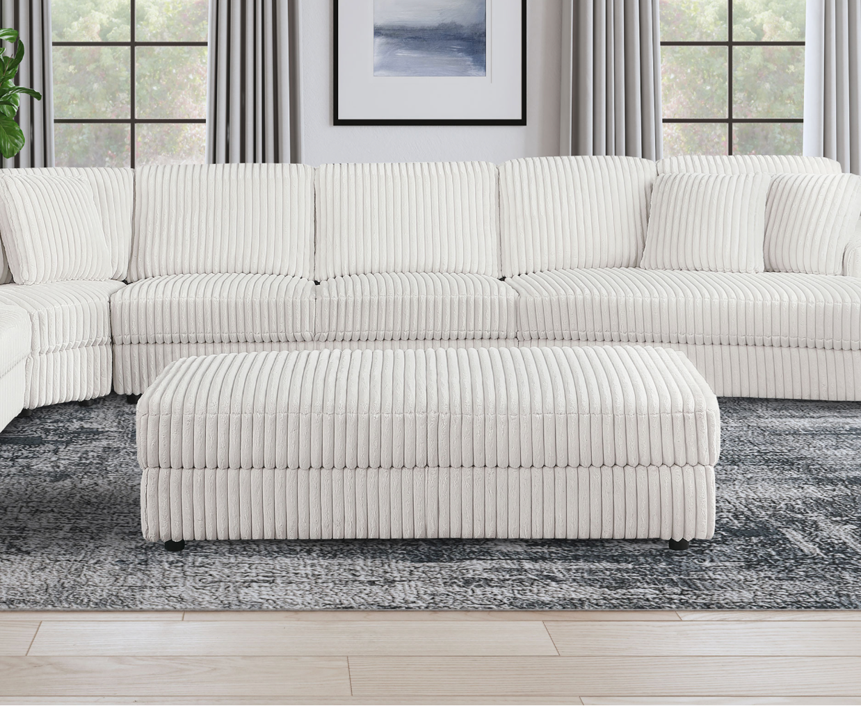 A living room with a sectional couch , ottoman , and rug.