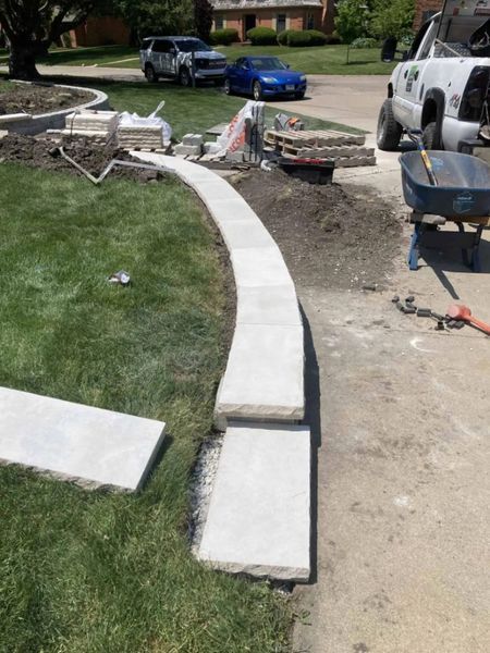 Construction of a curved concrete pathway in a residential yard.