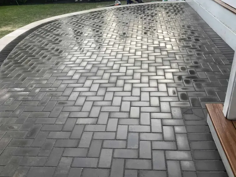 Brick patio in a herringbone pattern, grey blocks, near a house.