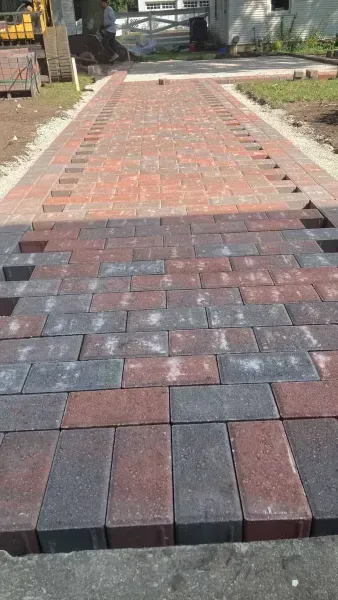 A brick walkway being installed; red and gray bricks, outdoor setting.