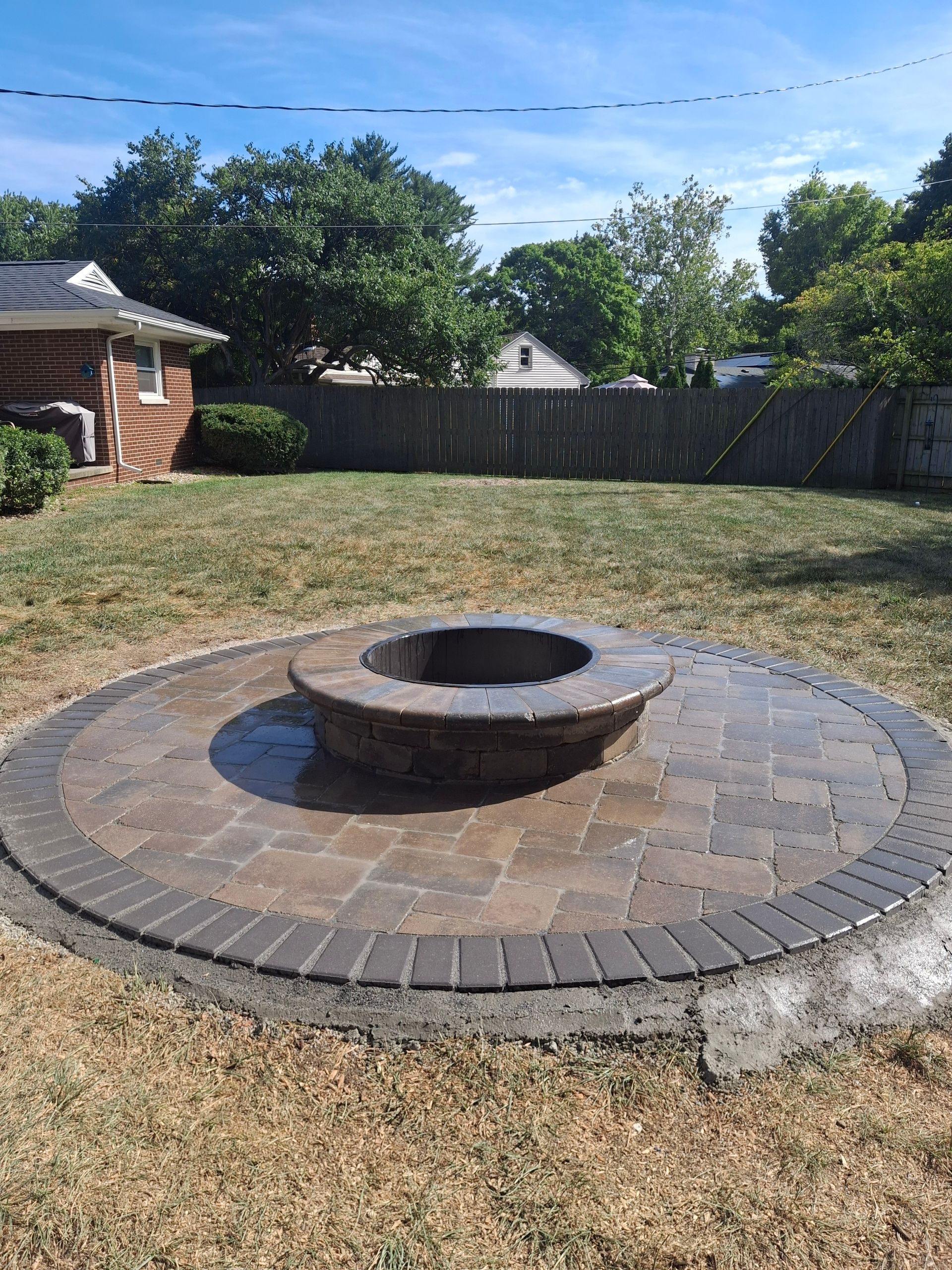 Circular brick fire pit in a backyard.